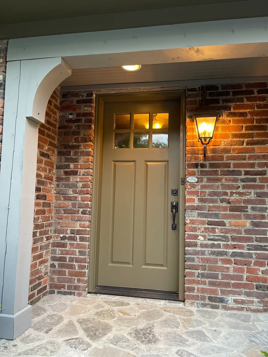 Front door painted olive green against red brick in Nashville TN